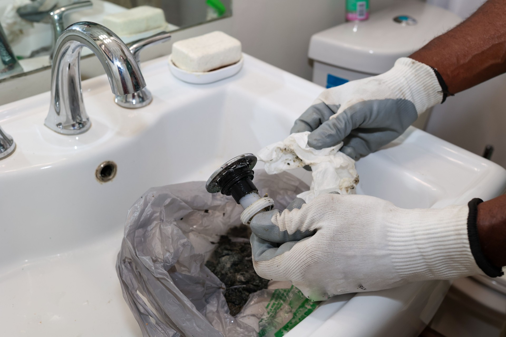 Black man cleaning clogged bathroom sink pipe